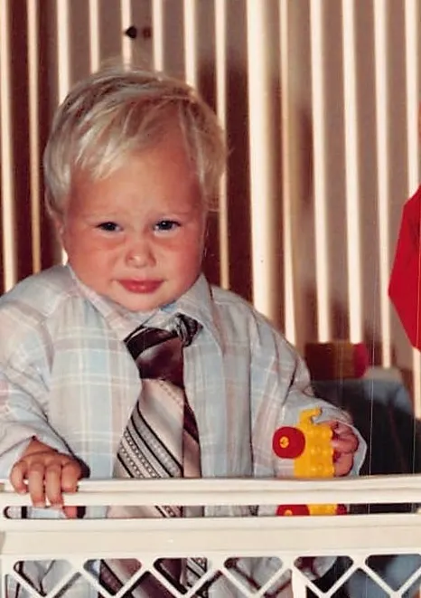 Joshua Herrington as a toddler in a dress shirt and necktie