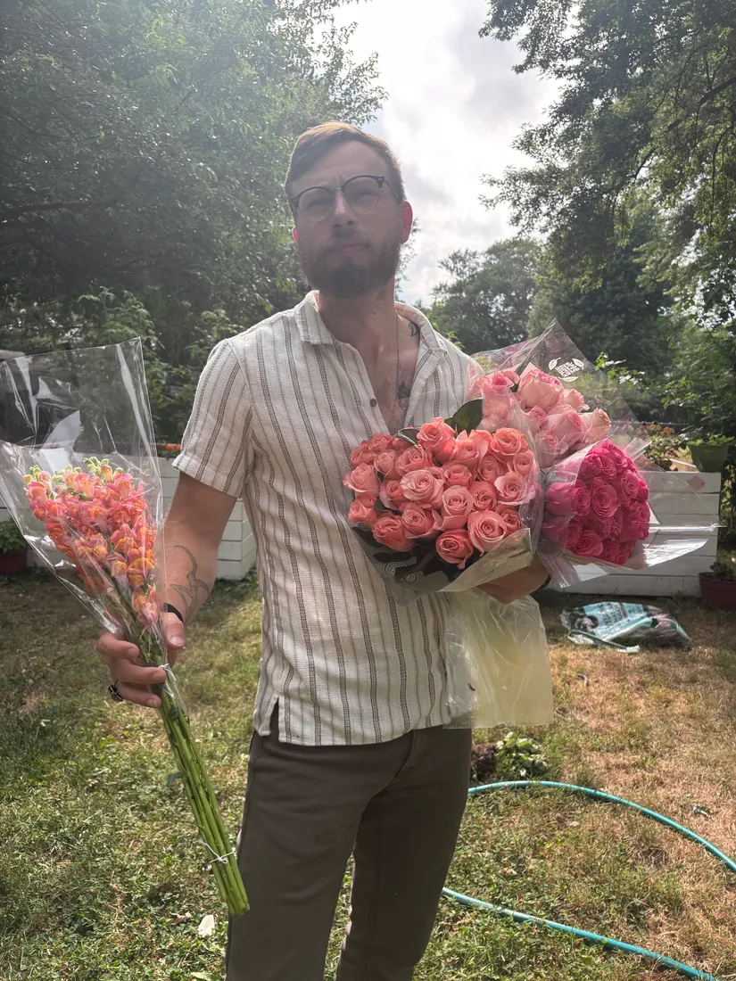 Joshua Herrington holding three bouquets in a backyard