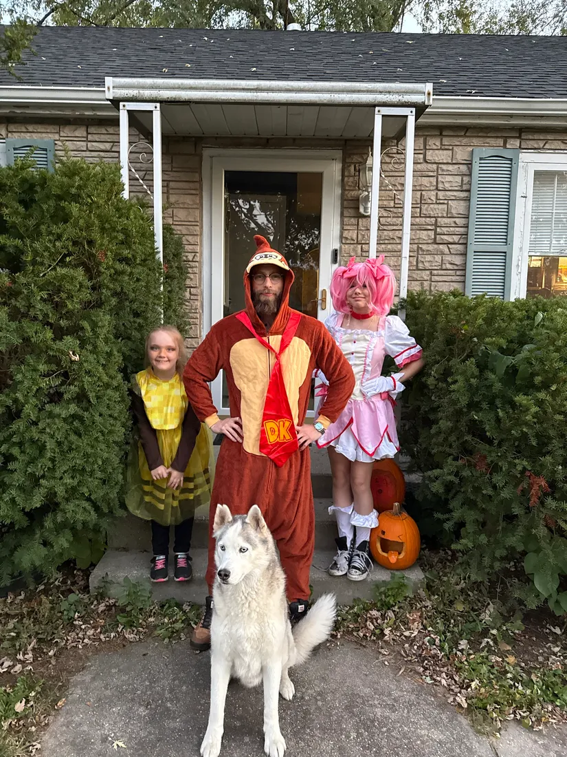 Joshua Herrington in a Donkey Kong costume with two children and a husky on Halloween