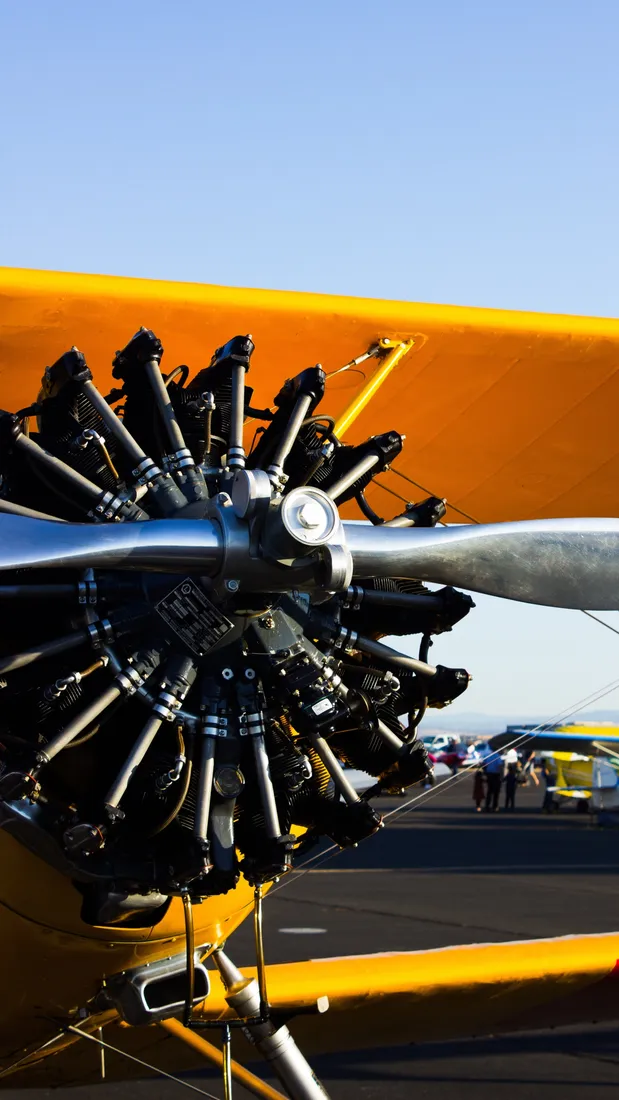 Close-up of a radial engine and propeller beneath a yellow biplane wing