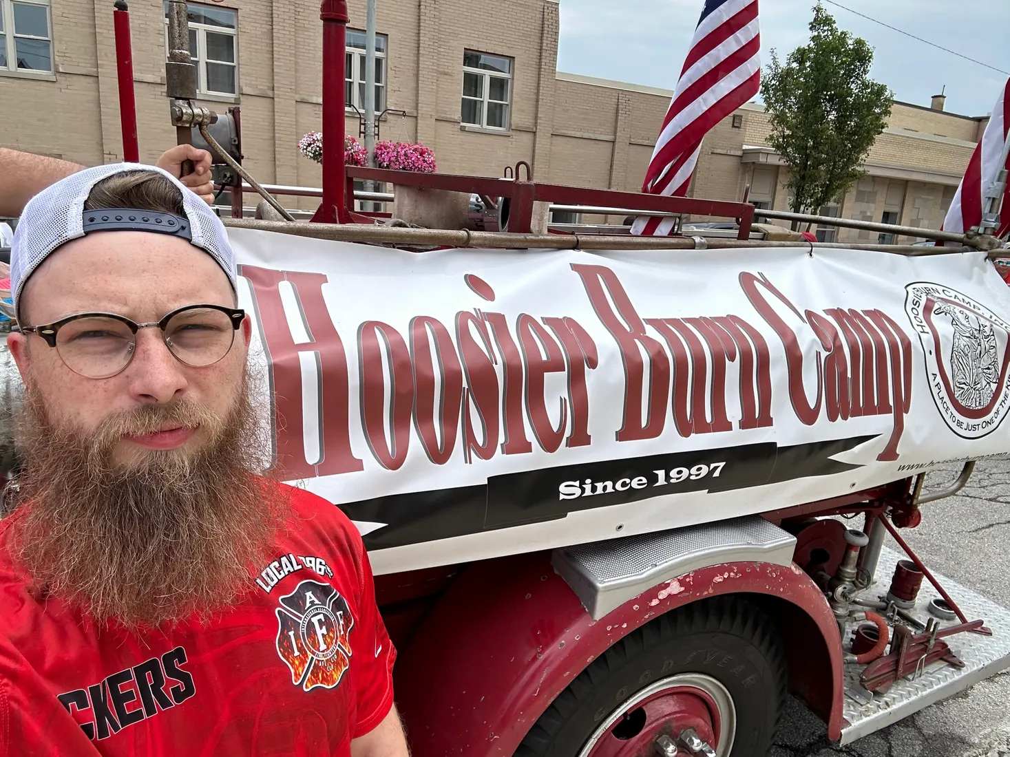 Joshua Herrington beside a vintage fire engine with a Hoosier Burn Camp banner