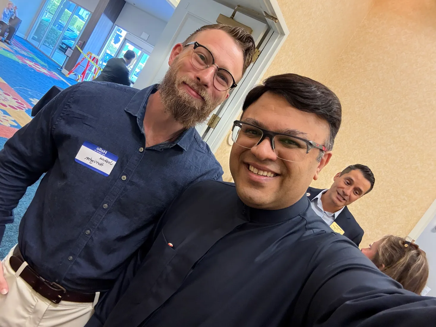 Joshua Herrington at an industry event, name tag reversed in a front-camera selfie